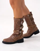 Bota de cuero color marrón con caña media, suela de goma negra, cierre lateral y hebillas ajustables. Presenta detalle trenzado en el talón.