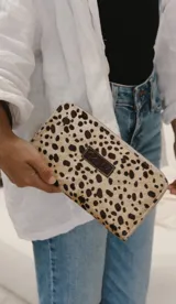 Billetera con estampado de animal print en tonos beige y marrón, con cierre.