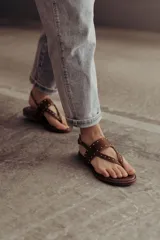 Sandalias marrones de cuero con tiras, microtachas doradas y hebilla lateral.