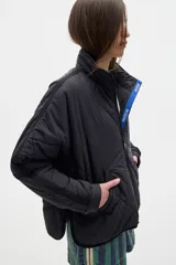 Campera acolchada color crema con cierre frontal y cuello alto. Presenta dos franjas azules en las mangas y ribete azul en el cuello y ruedo.