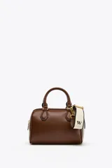 Bolso marrón formato city con asa doble de mano con detalles metálicos y correa interior extraíble en tejido canvas con posición bandolera. Bolsillo interior con cierre mediante cremallera metálica.