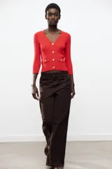 Chaqueta de punto roja con escote en pico, manga francesa y cierre frontal con botones dorados.