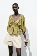 Top amarillo con estampado floral en jacquard, escote en pico, mangas cortas abullonadas con elástico, cintura elástica y espalda descubierta ajustable con lazos.