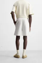 Bermuda relaxed fit color blanco confeccionada en tejido interlock de algodón con elasticidad. Cintura elástica ajustable con cordón interior. Bolsillos laterales y detalle de bolsillo trasero de plastrón.