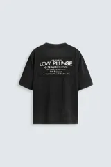 Camiseta negra de corte holgado, cuello redondo y manga corta. Estampado frontal con texto en blanco y parche rectangular en la espalda. Efecto lavado.