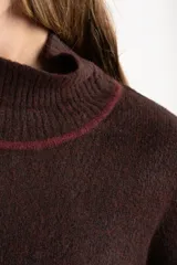 Sweater negro de tejido grueso con cuello alto acanalado. Presenta una franja decorativa en las mangas y el cuello en hilo marrón con brillo (lurex).