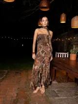 Vestido largo de fiesta con estampado abstracto en tonos marrones, escote strapless, cuerpo fruncido y falda con volados y tajo lateral.