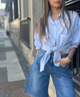 Camisa celeste a rayas blancas con mangas abullonadas y nudo en la parte delantera.