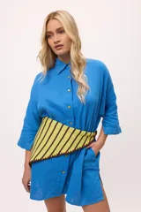 Vestido camisero a rayas verticales de colores pastel, con cuello camisero, cierre frontal con botones y mangas largas.