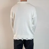 Sweater tejido color crudo, de corte holgado, con cuello redondo y terminaciones rotas en puños y ruedo.