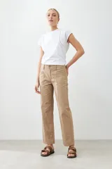 Pantalón recto color tostado con pespuntes verticales y cinturón de cuero marrón con hebilla dorada.