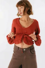 Blusa blanca de lino con escote en V, mangas largas abullonadas y frunce central.