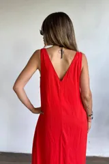 Vestido largo rojo vibrante, de corte holgado y sin mangas, con escote en V pronunciado y bolsillos laterales.