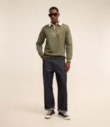 Sweater verde oliva de algodón y poliéster con cuello polo blanco, mangas largas y lettering bordado en el frente.