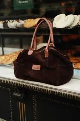 Bolso de viaje color verde oliva con detalles en cuero marrón.