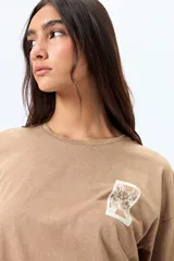 Remera negra de corte amplio con mangas cortas y cuello redondo. Presenta un pequeño estampado rectangular en el pecho y un estampado grande en la espalda con motivos japoneses.