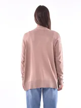 Saco color beige de tejido de punto, con cuello abierto, bolsillos frontales y mangas largas con detalle de botones en los puños.