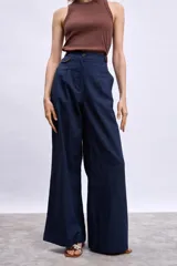 Pantalón ancho de tiro alto color azul marino, con pliegues frontales y ribetes en color naranja quemado en los bordes del bolsillo y la cintura.