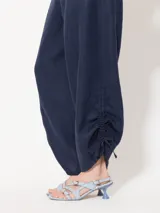 Pantalón largo de lino color blanco, de corte amplio y tiro alto. Presenta recortes en delantero y espalda, bolsillos escondidos al frente y bolsillos ojal en la parte posterior. Lleva jareta con lazo para ajustar y bordado marcario JCH en el delantero.