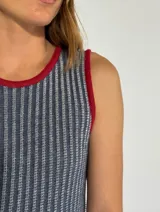 Vestido largo a rayas verticales color gris y blanco, con cuello en V y ribete amarillo. Presenta aberturas laterales con ribete amarillo.