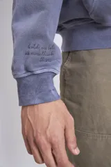 Buzo canguro con capucha color lila, de friza gastada.