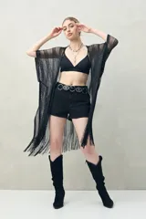 Poncho negro de tejido calado con flecos en el ruedo.