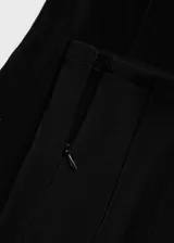 Pantalón negro de tejido de punto ligero con cintura elástica, corte slim fit, diseño largo, detalle de costuras y cierre con cremallera en los bajos.