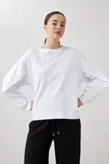 Sweatshirt blanco de manga larga con cuello redondo y puños elásticos.