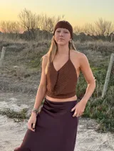 Top de crochet en hilo marrón con acabado brilloso. Diseñado con espalda libre y tiras ajustables que se atan atrás, este top realza la figura y suma un toque bohemio y sofisticado a cualquier look.