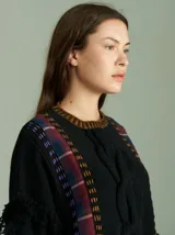 Sweater negro oversize de lana con cuello redondo, bordado central en forma de trenza, laterales con cuadrillé y mangas acampanadas desflecadas.