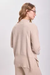 Sweater de punto color beige, con cuello alto y mangas largas.