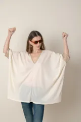 Blusa italiana color crema, tipo poncho, con escote en V con lurex, mangas 3/4 y puños ajustados.
