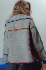 Chaqueta gris de paño de lana con detalles de crochet de colores en los bordes. Corte cuadrado y mangas 3/4 amplias.