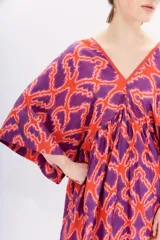 Vestido largo de viscosa estampada en tonos naranja y violeta. Tiene mangas al codo, calce holgado y recorte en la cintura con frunces.