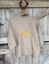 Remera de manga corta y cuello redondo, color beige claro, con un bordado central que representa el Sol de Mayo con el texto "REPUBLICA ORIENTAL DEL URUGUAY" y "EST. 1825".