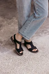 Sandalia plana de color tostado confeccionada en una combinación de neopreno y cuero. Posee un diseño de tira ancha con aberturas sobre el empeine, plantilla acolchada y suela de goma con costuras a la vista.