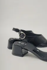 Sandalia de cuero con acabado brillante color marrón rojizo, taco ancho de altura media y punta cuadrada. Presenta tiras anchas cruzadas en el empeine y tira fina con hebilla ajustable en el tobillo.