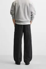Pantalón de jean negro, corte relaxed fit, con bolsillos frontales y traseros tipo parche, tira multifunción y bolsillo tipo parche en las piernas. Tiene efecto lavado y cierre frontal con cremallera y botón.