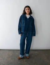 Conjunto de jean azul marino oscuro, compuesto por una chaqueta de corte holgado y un pantalón de tiro medio-bajo con corte vertical.
