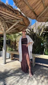 Pollera larga color marrón, con fruncido en la cintura, transparencias y volados verticales en la abertura lateral.