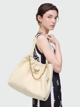 Bolso tipo tote de cuero color crema, con frunce superior y asas de hombro. Presenta un pequeño bolsillo frontal con cierre metálico dorado y un dije de llave colgante.