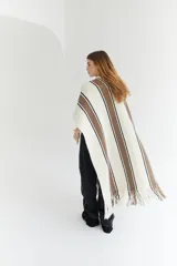 Ruana artesanal color beige con rayas horizontales rojas y amarillas, y flecos en el borde inferior.