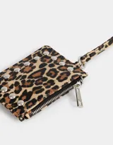 Monedero de cuerina con estampado animal print, correa lateral y aplique de tachas decorativas. Cuenta con cierre superior y correa lateral.
