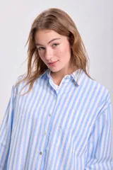 Camisa celeste con rayas verticales blancas, de corte oversize y manga larga.