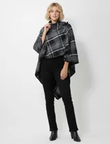 Capa corta de tejido grueso, color verde esmeralda con diseño de cuadros escoceses en azul marino y líneas finas en beige. Posee cuello alto que se cruza al frente y se cierra con un broche oscuro.