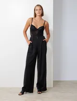 Pantalón palazzo de satén color negro, tiro alto, con pretina delantera con pasadores, botón y cierre, pretina trasera elastizada y bolsillos verticales delanteros.