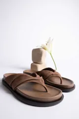 Sandalias de cuero color verde oliva, con tira ancha superior con detalle de frunce y suela plana.