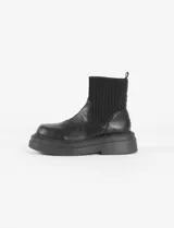 Botas negras de cuero sintético con caña elastizada y suela track.
