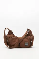 Cartera tipo shoulder color marrón, con diseño utilitario y múltiples bolsillos con cierre en el frente y laterales. Tiene una correa regulable para llevar al hombro o cruzada.