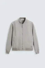 Cazadora bomber ligera gris confeccionada en tejido técnico. Cuello y puños en rib elástico, manga larga, bolsillos de vivo en cadera y bolsillo interior. Cierre frontal con cremallera.